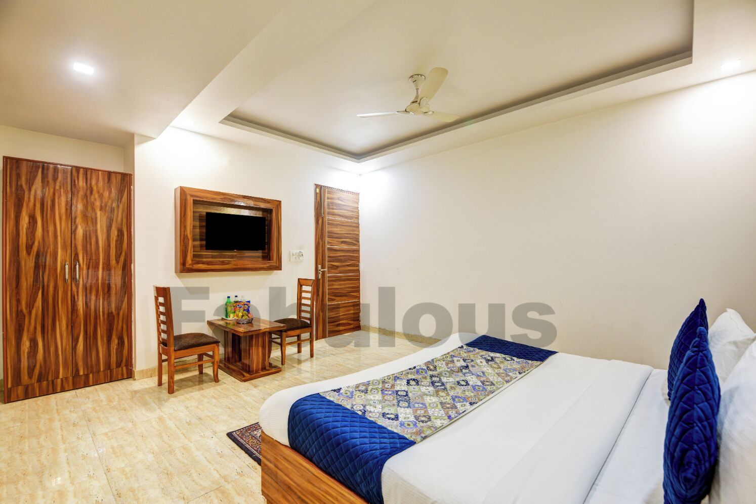 A bedroom with a bed, a desk, a chair, a wardrobe, and a television.