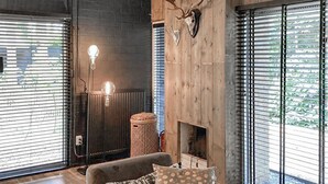 Une pièce chaleureuse avec une cheminée, un tapis à motifs et une grande tête de cerf accrochée au mur.