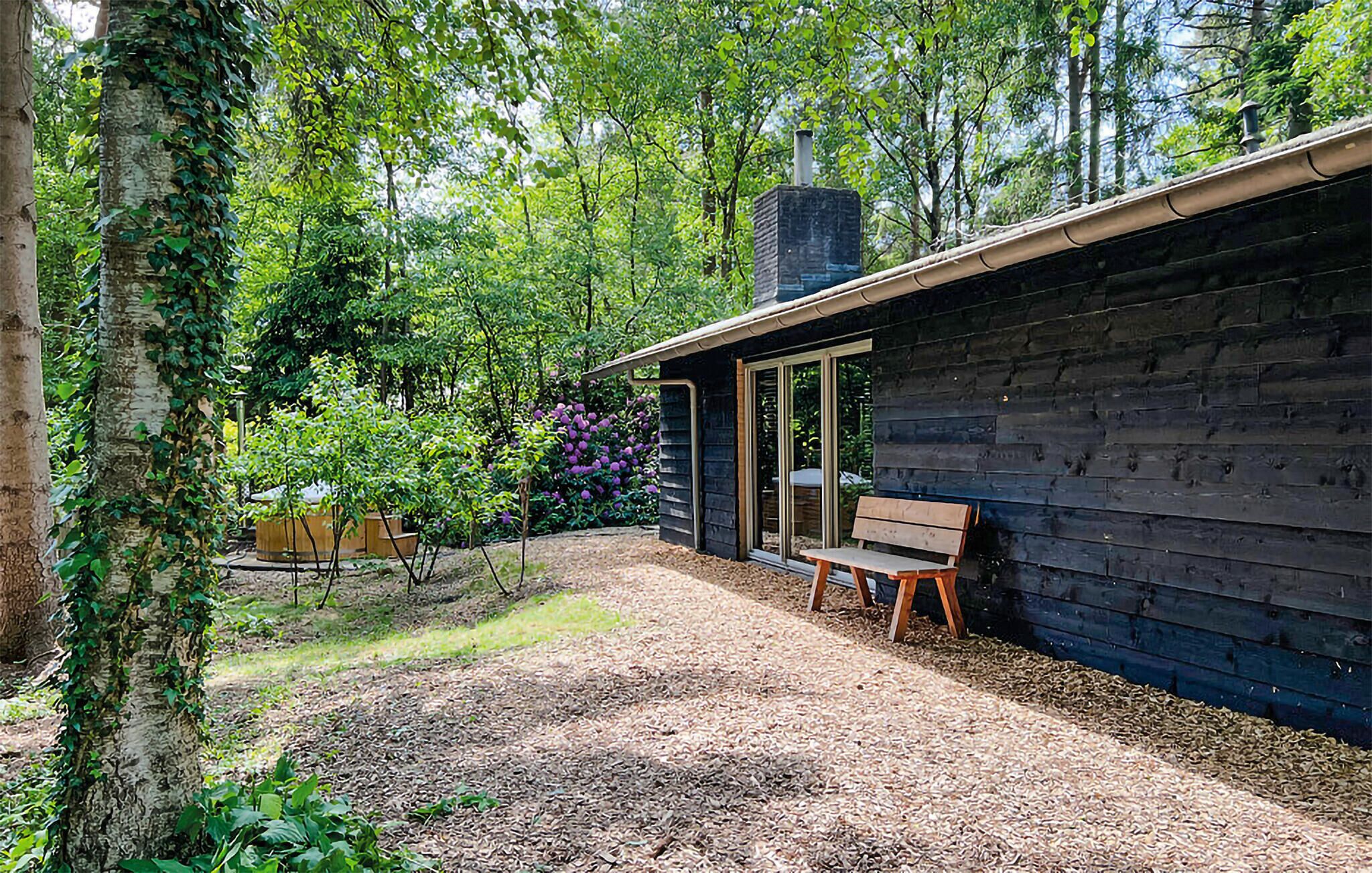 Une cabane avec une façade en bois, une cheminée et un banc à l’extérieur.