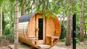 Une structure de sauna en bois, dotée d’une porte, de deux bancs et d’une petite plateforme.