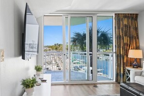 A modern living room with a large sliding glass door leading to a balcony with a marina view.