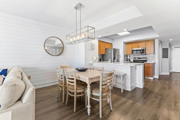 A modern kitchen with white cabinetry, a central island, and a dining area with a wooden table and chairs.