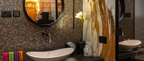 Une salle de bain moderne avec un grand miroir, deux lavabos et un vase décoratif rempli de fleurs.