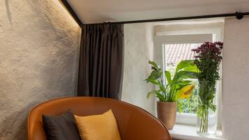 A cozy corner with a brown leather chair, a small table with fruits and a potted plant by a window.