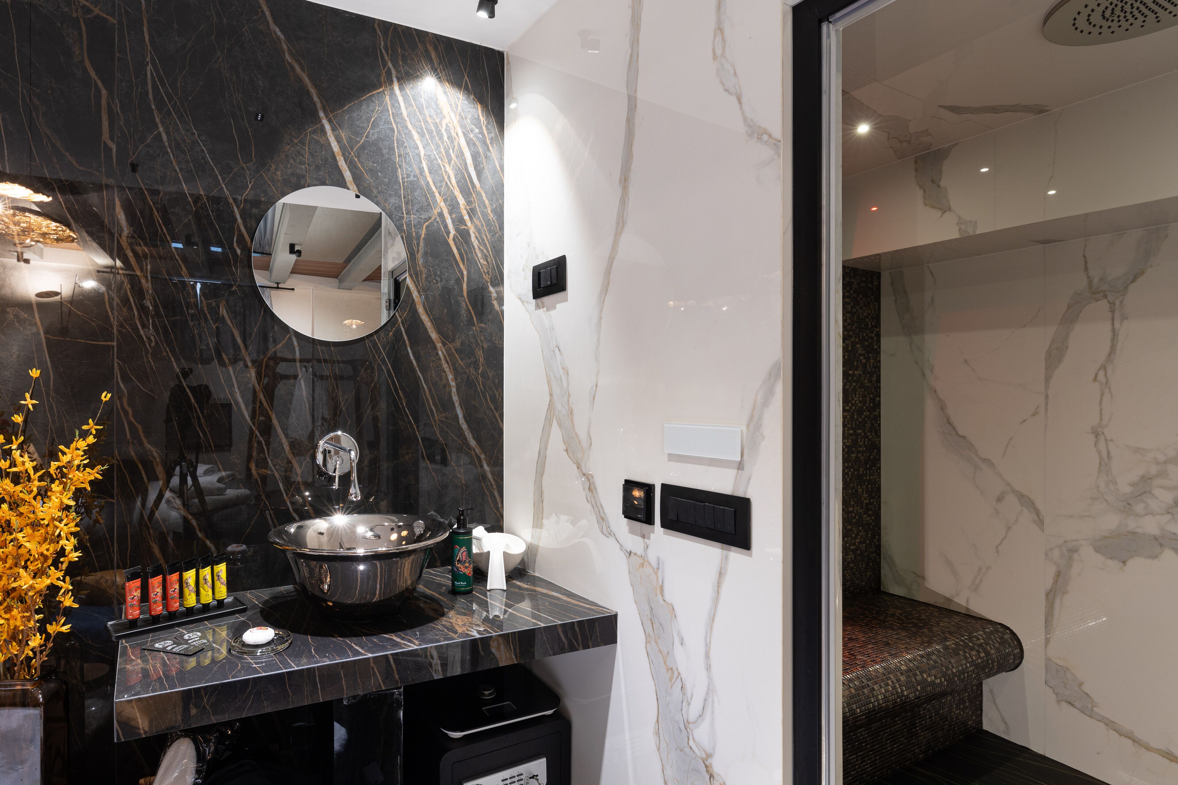 A modern bathroom with a marble sink, a mirror, and a shower area.