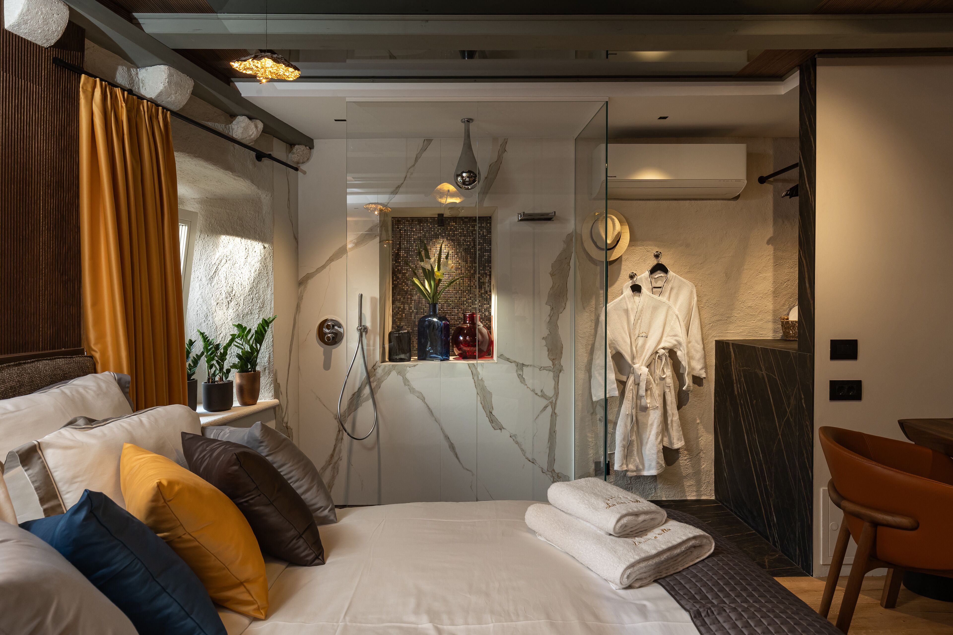 Camera d'albergo moderna con un letto, cuscini, zona doccia e appendiabiti.
