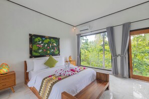 A bedroom with a bed, a nightstand, a window with curtains, and a painting on the wall. - Radjes Bungalow Nusa Penida (Penida Island)
