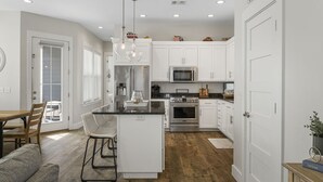 A modern kitchen with white cabinetry, stainless steel appliances, and a central island. - 2 Master bedrooms, Steps to the beach, private pool (Panama City Beach)