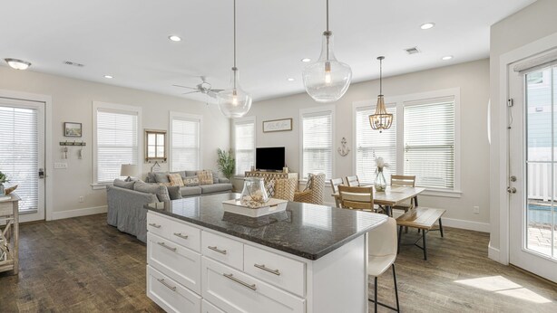 A spacious kitchen with a central island, a dining area with a wooden table and chairs, and a living area with a sofa and TV. - 2 Master bedrooms, Steps to the beach, private pool (Panama City Beach)