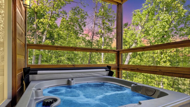 A hot tub with a wooden deck and a view of trees. - Luxury Cabin with Indoor Pool, Hot Tub, Views, Games, Fire Pit, Covered Decks! (Sevierville)