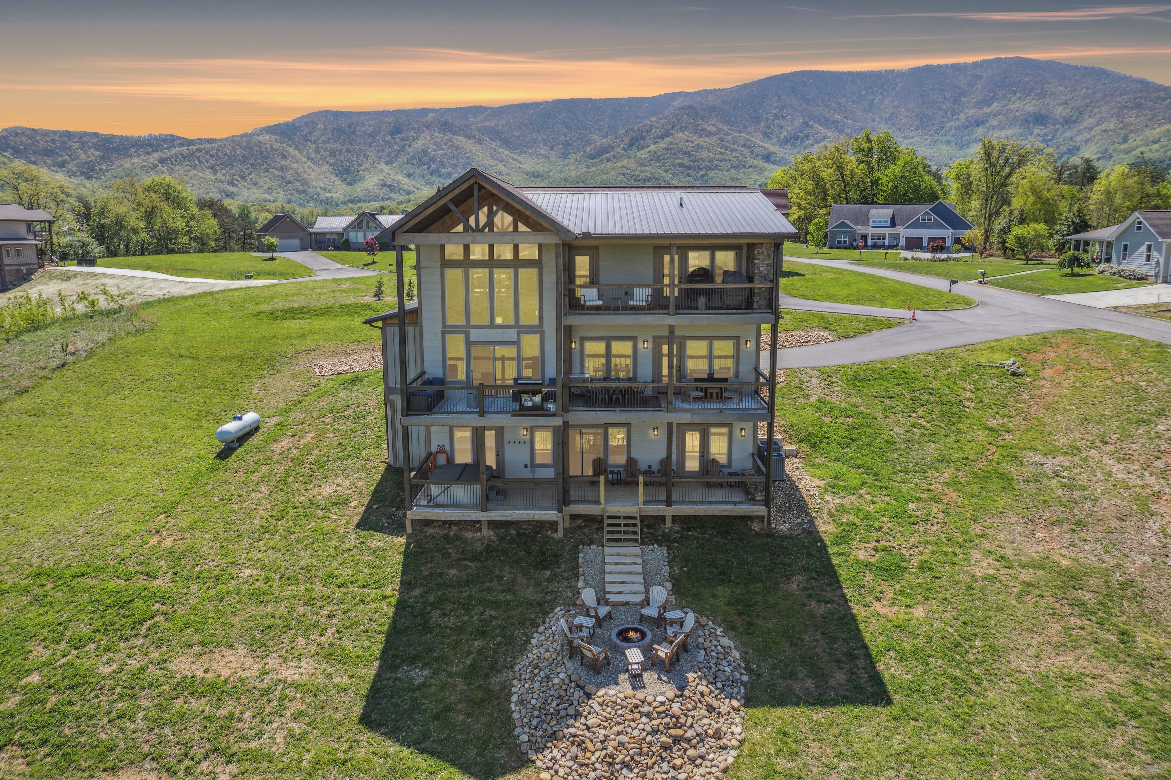 A multi-story house with a large deck, a fire pit, and a view of mountains.