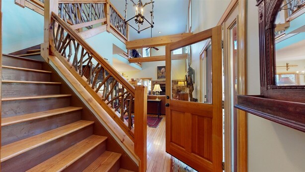 A wooden staircase with a railing, leading to a room with a stone fireplace and a lamp. - The Lodge That Ruins Every Other Rental For You | Laughing Bear Lodge (Highlands)