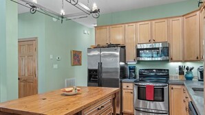 A kitchen with wooden cabinets, stainless steel appliances, and a wooden island. - The Lodge That Ruins Every Other Rental For You | Laughing Bear Lodge (Highlands)