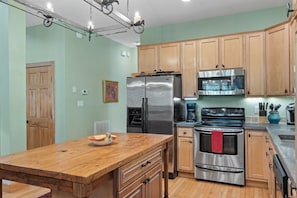 A kitchen with wooden cabinets, stainless steel appliances, and a wooden island.