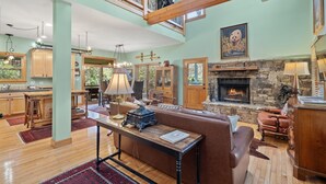 A spacious living area with a stone fireplace, wooden furniture, and a high ceiling with exposed beams. - The Lodge That Ruins Every Other Rental For You | Laughing Bear Lodge (Highlands)