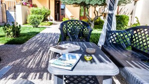 An outdoor seating area with a table and chairs, a book, and a glass of water. - Affitacamere Domo - Luci (Nurachi)