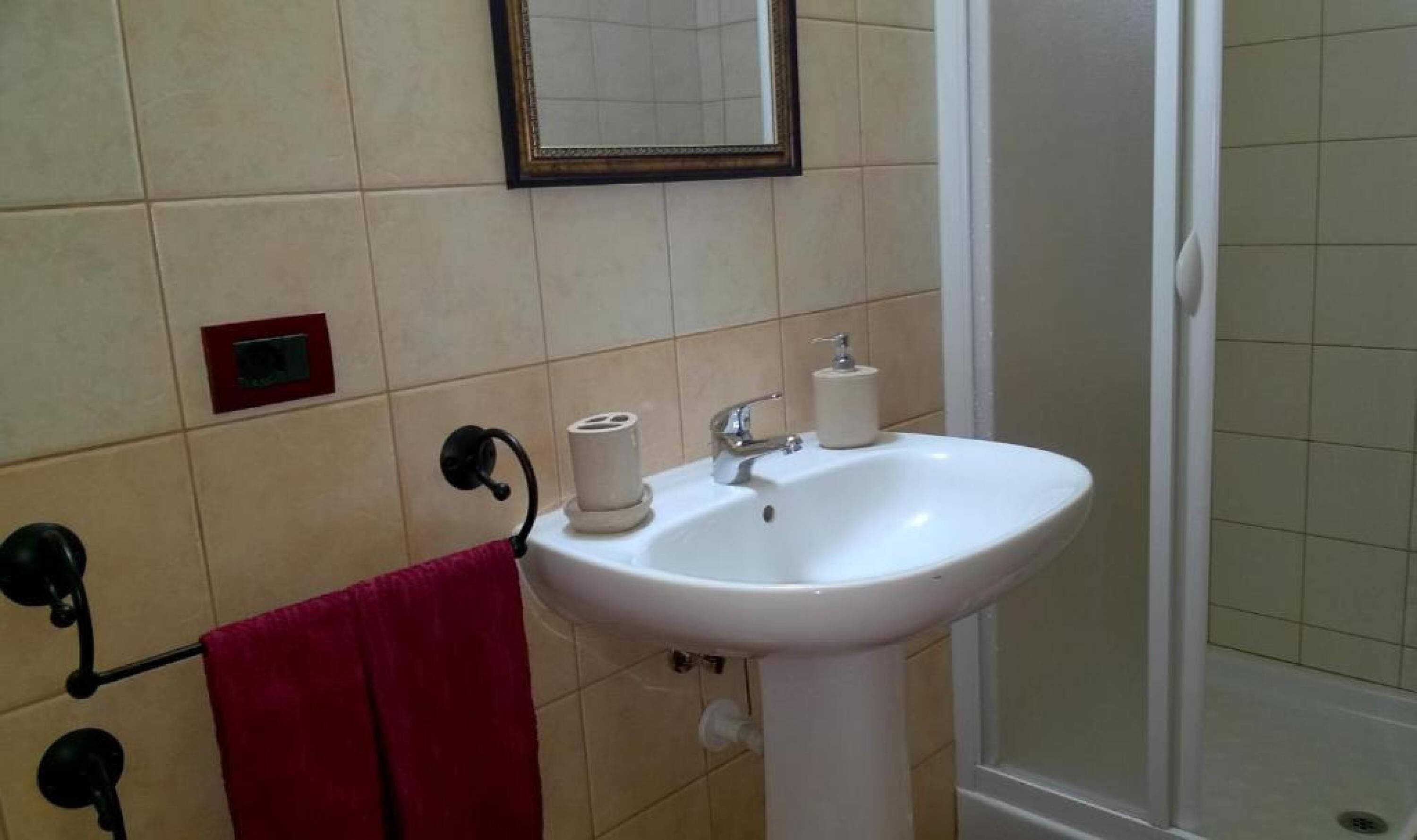 A bathroom with a white sink, a mirror, and a red towel hanging on a rack.