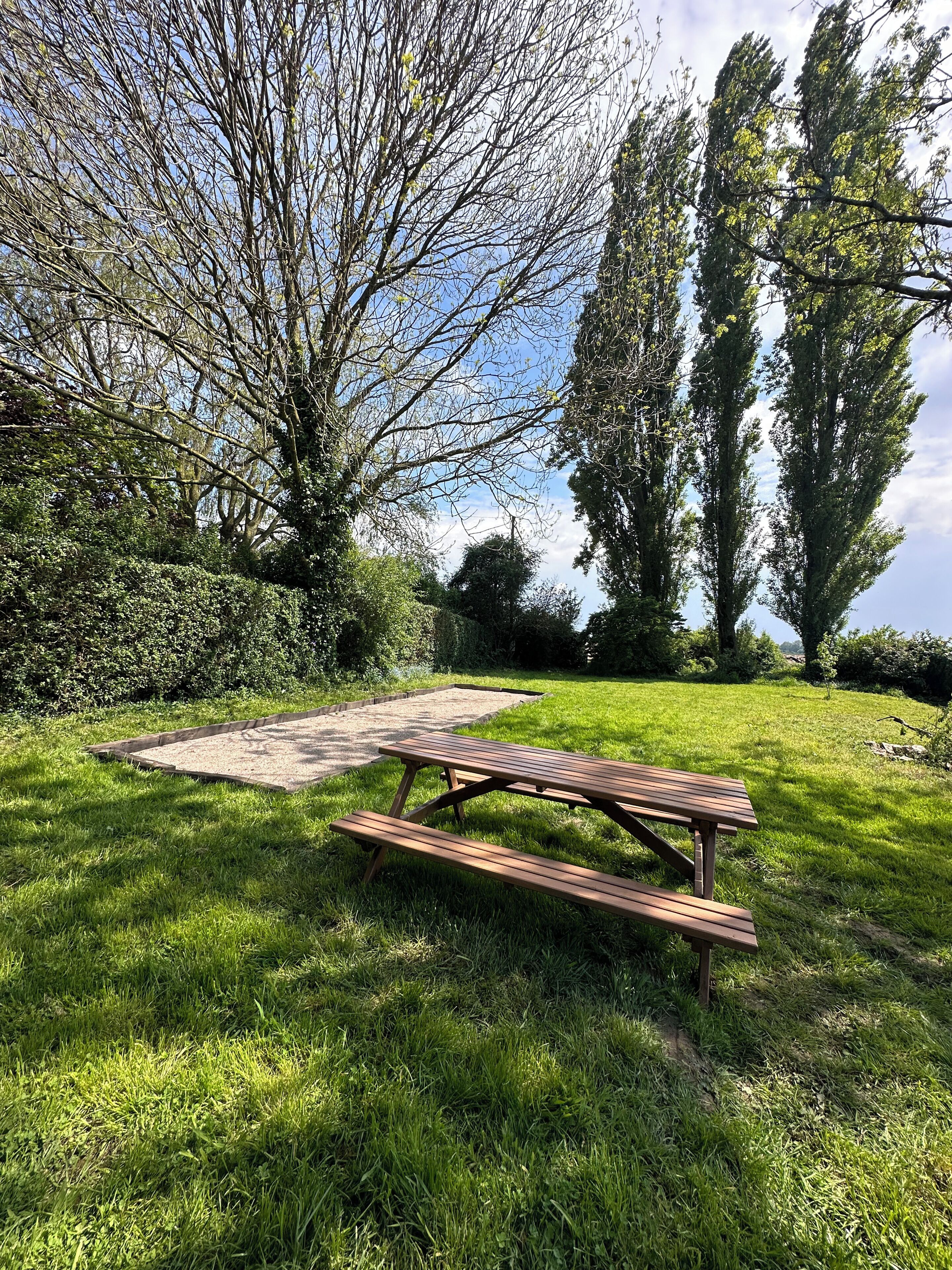 Une table de pique-nique dans un espace verdoyant, avec des arbres et un ciel dégagé.