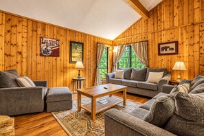 A cozy room with wooden paneling, a sofa set, a coffee table, and a rug.