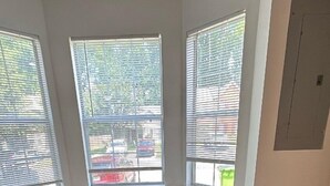 A beige sectional sofa with plaid cushions in a room with three windows. - Cozy 2BR Home Near Atlanta, Six Flags and Trails (Mableton)