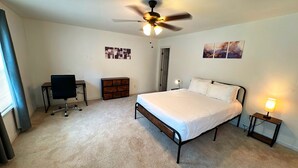 A bedroom with a bed, a desk, a chair, a dresser, and a ceiling fan. - Cozy 2BR Home Near Atlanta, Six Flags and Trails (Mableton)