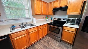 A kitchen with wooden cabinets, a stainless steel sink, a stove, and a toaster. - Cozy 2BR Home Near Atlanta, Six Flags and Trails (Mableton)