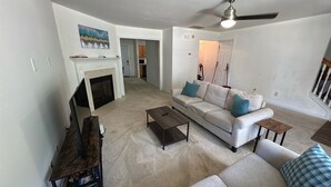 A living room with a fireplace, a sofa, a coffee table, and a TV stand. - Cozy 2BR Home Near Atlanta, Six Flags and Trails (Mableton)