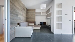 Una sala de estar moderna con un sofá modular, un televisor de pantalla plana y estanterías empotradas.