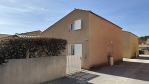 Un edificio de una planta con fachada color crema, una ventana pequeña y una puerta blanca.