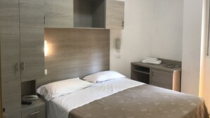 Une chambre à coucher comprenant un lit, une table de chevet, une armoire et une petite table avec une serviette.