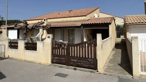 Una casa residencial con techo de tejas, entrada protegida por una reja y una antena parabólica.