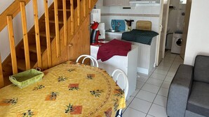Una cocina compacta con armarios blancos, un hervidor rojo y una toalla verde sobre la encimera.