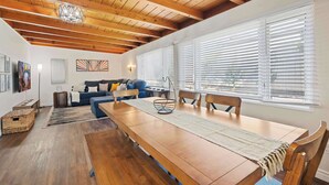 A spacious living area with a wooden ceiling, a long dining table, and a sofa. - Sweet Escape | Family Retreat | Vibrant  | Spa (San Diego)