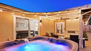 A hot tub with a waterfall feature, outdoor seating, and string lights. - Sweet Escape | Family Retreat | Vibrant  | Spa (San Diego)