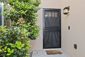 Enter a serene space with a welcoming entrance featuring a decorative glass panel and lush greenery.