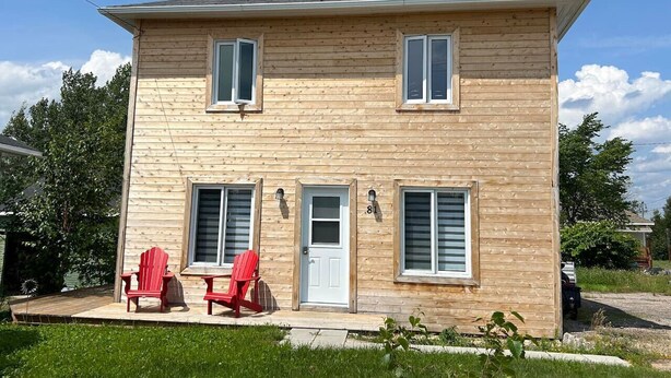 A two-story wooden house with a front porch, two windows on the upper floor, and a door with a small window. - Le Havre du Pilote Aux Bergeronnes (Grandes-Bergeronnes)