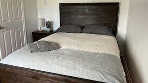 En säng med en mörk sänggavel, ett beige överkast och två kuddar.
