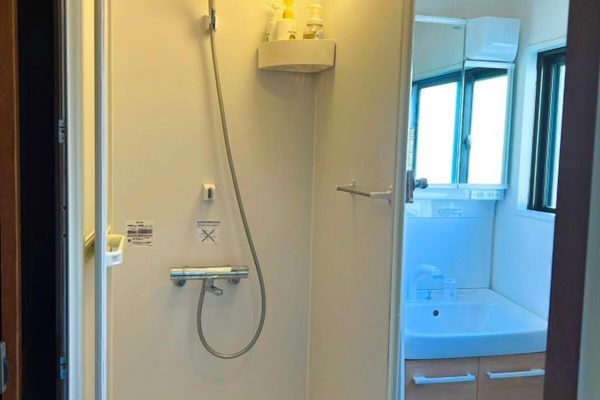 A bathroom with a shower, a sink, and a window.