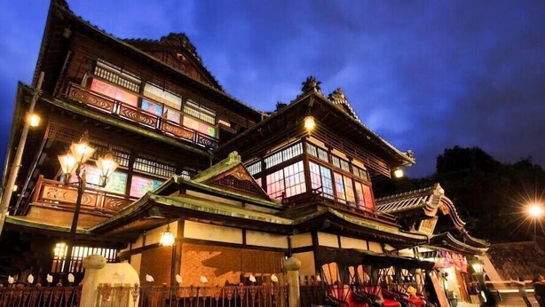 A traditional building with multiple levels and ornate wooden details, illuminated by exterior lights. - Himerakuen (Matsuyama)