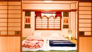 A traditional Japanese-style room with tatami flooring, a shoji screen, and a futon bed with a red and blue blanket. - Himerakuen (Matsuyama)