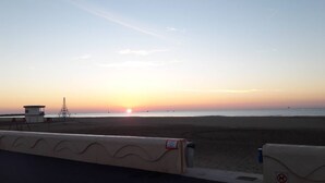 A beach with a lifeguard tower and a clear view of the sunset over the ocean.