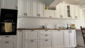 A kitchen with white cabinets, a black oven, and a wooden countertop.