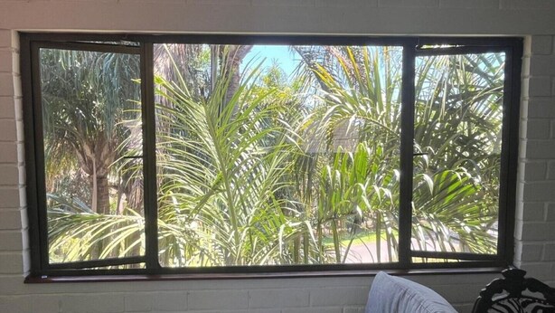 A room with a large window offering a view of tropical plants. - The Treehouse (Amanzimtoti)