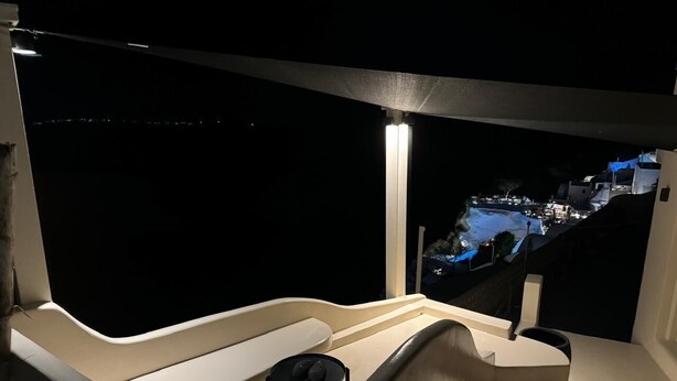 En moderne, veloplyst balkon med udsigt over et bybillede om natten.