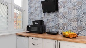 Une cuisine équipée d’un four à micro-ondes, d’une machine à café et d’un panier à fruits posé sur le comptoir.