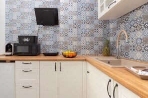 A kitchen with patterned backsplash, a microwave, a toaster, a sink, and a fruit bowl. - Modern Studio in the Heart of Gdansk | A Place to Work (Gdańsk)