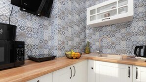 Une cuisine avec des carreaux décoratifs, un four à micro-ondes, un panier de fruits, un évier et un meuble de rangement.