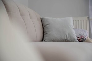 A white upholstered sofa with a grey pillow and a floral-patterned blanket. - Functional Apartment | Parking, Balcony, Close to Park (Wroclaw)