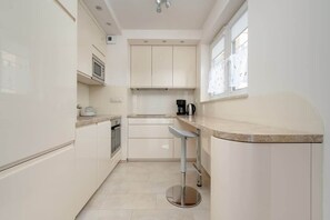 Una cocina moderna con armarios blancos, microondas, cafetera y ventana.