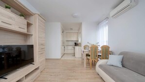 En moderne stue med et fladskærms-tv, træmøbler, en sofa og et spiseområde med stole.
